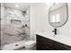 Modern bathroom with a stylish vanity, oval mirror, and a walk-in shower featuring elegant marble-like tile at 5951 W Granada Rd, Phoenix, AZ 85035