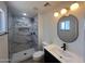 A bathroom with marble-look tiling in the shower, an oval mirror, and modern fixtures at 5951 W Granada Rd, Phoenix, AZ 85035