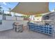 Inviting backyard grilling area with shade structure, a built-in grill, seating, and a privacy wall at 908 E State Ave, Phoenix, AZ 85020