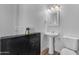 Bright half bath with pedestal sink, toilet, and cabinet, perfect for guests at 908 E State Ave, Phoenix, AZ 85020