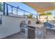 Outdoor kitchen features stainless steel grill, refrigerator, bar seating and shade awning at 908 E State Ave, Phoenix, AZ 85020