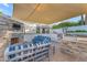 Charming outdoor living space features stone fireplace, grill, shade awning and blue striped sofa seating at 908 E State Ave, Phoenix, AZ 85020
