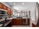 Open kitchen area with stainless steel appliances, wood cabinets, a breakfast bar, and a view of the living area at 1102 N 5Th St, Buckeye, AZ 85326
