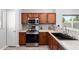 Modern kitchen with stainless steel appliances, a stylish backsplash, wood cabinets, and a sink overlooking the window at 1102 N 5Th St, Buckeye, AZ 85326