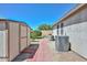 Neat backyard featuring a shed, brick pathway, manicured lawn, and modern air conditioning unit at 11580 N 86Th Ln, Peoria, AZ 85345