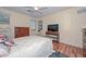 Cozy bedroom featuring wood-look flooring, dresser, ceiling fan, and large television at 11580 N 86Th Ln, Peoria, AZ 85345