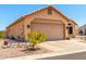 Side view of a tan home featuring a two-car garage and desert landscaping at 11631 W Lemon Ct, Surprise, AZ 85378