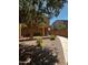 View of a backyard with a covered patio, fence, and rock landscape, with some sparse greenery at 1350 S Greenfield Rd # 1221, Mesa, AZ 85206