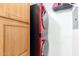 A tidy laundry area with stacked red washer/dryer and wood-faced storage cabinets at 14000 N 94Th St # 2187, Scottsdale, AZ 85260