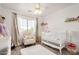 Cozy Bedroom featuring a white crib, comfortable armchair, soft rug, and natural light from the window at 15006 N 172Nd Ln, Surprise, AZ 85388