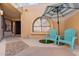 Cozy front patio with blue Adirondack chairs, striped umbrella, and stone flooring at 16648 N 30Th Ave, Phoenix, AZ 85053