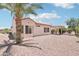 The backyard features desert landscaping, a covered patio and mature palm tree at 20234 N Mariposa Way, Surprise, AZ 85374