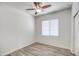 Bright, minimalist bedroom with ceiling fan, wood-look floors and a large window at 20410 N Mac Neil St, Maricopa, AZ 85138