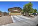 Tan single-Gathering home featuring a two-car garage, desert landscaping, and a tree-lined front yard at 20410 N Mac Neil St, Maricopa, AZ 85138