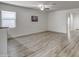 Open-concept living room featuring sleek wood-look flooring, a bright window, and freshly painted white walls at 20410 N Mac Neil St, Maricopa, AZ 85138