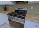 Close-up of stainless steel range with granite countertop and glass backsplash at 6714 E Nightingale Cir, Scottsdale, AZ 85266
