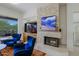 Inviting living room featuring a stone fireplace, plush blue chairs, and a view to the outdoor patio at 6714 E Nightingale Cir, Scottsdale, AZ 85266