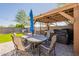 This backyard has turf, pavers, a wood covered patio, a hot tub, and a dining table with an umbrella at 7238 N 126Th Ln, Glendale, AZ 85307