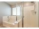 Bathroom featuring a glass enclosed shower and large bathtub with window at 7238 N 126Th Ln, Glendale, AZ 85307