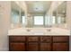 Bathroom with double sinks and a large mirror over a wood cabinet at 7238 N 126Th Ln, Glendale, AZ 85307