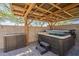 Relax in this backyard hot tub located under a covered patio with wood beams and string lights at 7238 N 126Th Ln, Glendale, AZ 85307