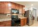Kitchen showcasing stainless steel fridge, black appliances, and dark wood cabinetry at 7238 N 126Th Ln, Glendale, AZ 85307