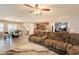 Open concept living room with brown sofa, ceiling fan, and dining area at 7238 N 126Th Ln, Glendale, AZ 85307