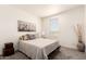 Comfortable bedroom with a large window, bed with decorative pillows, and neutral decor at 873 N Windy Meadow Ln, Maricopa, AZ 85139