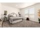 Serene bedroom featuring neutral tones, carpet flooring, and large windows for natural light at 873 N Windy Meadow Ln, Maricopa, AZ 85139