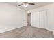 Neutral carpeted bedroom with a ceiling fan, closet, and a door leading to another room at 909 E Agua Fria Ln, Avondale, AZ 85323
