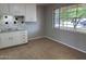 Cozy kitchenette features white cabinets, tile floors, and a bright window offering outdoor views at 3006 W Stella Ln, Phoenix, AZ 85017