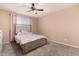 Neutral bedroom with a patterned carpet, ceiling fan and bed with upholstered headboard at 3529 W Saint Moritz Ln, Phoenix, AZ 85053