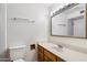 A clean bathroom featuring a toilet, sink with wood cabinets, a large mirror and shower area with a handrail at 414 E Westchester Dr, Tempe, AZ 85283