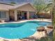 Backyard swimming pool with a water feature, brick patio, and lush landscaping at 45726 W Long Way, Maricopa, AZ 85139