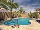 Inviting backyard pool with a table, stone waterfall, and mature palms perfect for relaxation and entertaining at 45726 W Long Way, Maricopa, AZ 85139