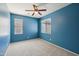 Bright bedroom with blue walls, carpeted floors, two windows, and a ceiling fan at 4712 E Bonanza Rd, Gilbert, AZ 85297