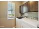 Bright laundry room featuring a window, upper cabinets, and modern washer and dryer units at 4712 E Bonanza Rd, Gilbert, AZ 85297