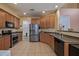 Well-lit kitchen with stainless steel appliances, ample wood cabinetry, and easy access to an adjacent room at 7246 W Monte Cristo Ave, Peoria, AZ 85382
