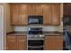 Modern kitchen featuring stainless steel appliances, including a range and microwave, with wood cabinetry and dark countertops at 7246 W Monte Cristo Ave, Peoria, AZ 85382