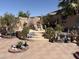 Picturesque backyard featuring mature trees, tiered hardscape, and whimsical garden decor at 9911 W Riverside Ave, Tolleson, AZ 85353