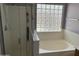 Modern bathroom with glass-enclosed shower and soaking tub with a window at 9911 W Riverside Ave, Tolleson, AZ 85353