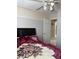 Bedroom featuring a queen-sized bed with a floral blanket and a ceiling fan, with a glimpse into the bathroom at 9911 W Riverside Ave, Tolleson, AZ 85353