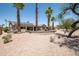 Spacious backyard featuring desert landscaping, patio, solar panels, and mature palm trees at 15953 W Catalina Dr, Goodyear, AZ 85395