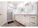 Bright bathroom featuring double sinks, white cabinets, modern fixtures, and a walk-in shower with glass door at 15953 W Catalina Dr, Goodyear, AZ 85395