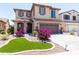 Charming two-story home featuring a well-manicured yard with vibrant pink flowers and decorative turf at 19461 N Rose Rd, Maricopa, AZ 85138