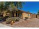 Side view of the tan home, showcasing desert landscaping and the fenced backyard at 23682 W Bowker St, Buckeye, AZ 85326