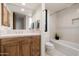 Bathroom with oak vanity, granite countertop, and bathtub with tiled wall at 39089 N 102Nd Way, Scottsdale, AZ 85262