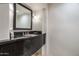 Half bath featuring a dark granite vanity and an ornate framed mirror at 39089 N 102Nd Way, Scottsdale, AZ 85262
