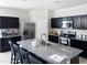 The kitchen has dark cabinets, stainless steel appliances, and a large center island with gray granite countertops at 42087 W Manderas Ln, Maricopa, AZ 85138