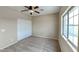 A bedroom is brightly lit by a ceiling fan and a window, with closet and carpet at 4776 W Eva St, Glendale, AZ 85302